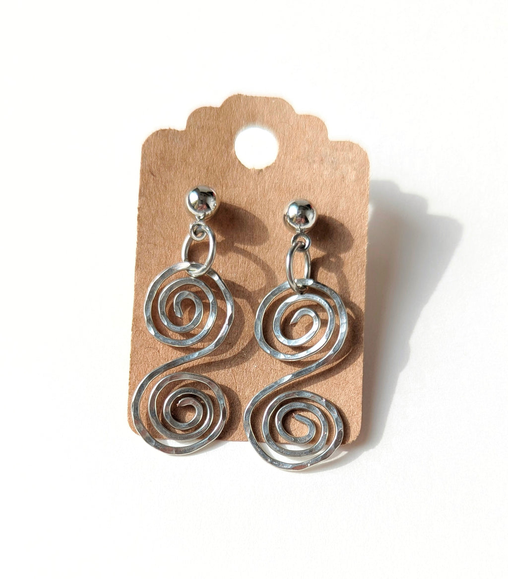 Silver spiral earrings on a cardboard backing with a white background