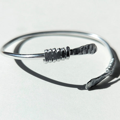 Silver bracelet with a unique design on a light gray background