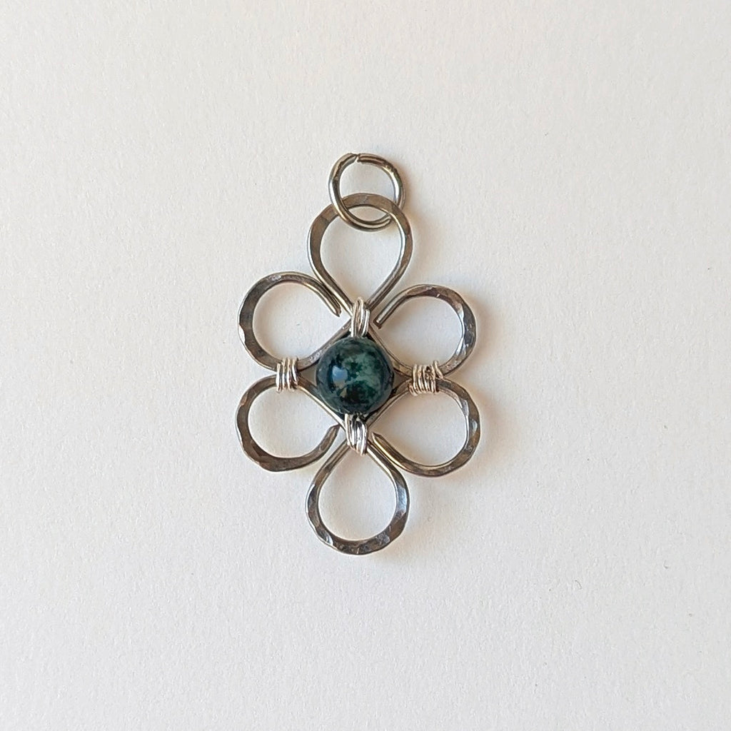 Silver floral pendant with a central gemstone on a light background