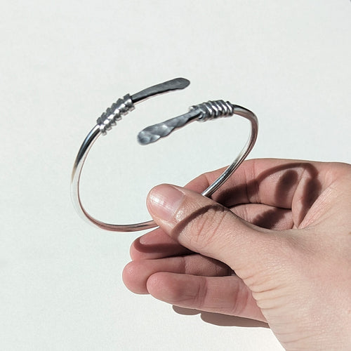 Hand holding a metal bracelet against a white background
