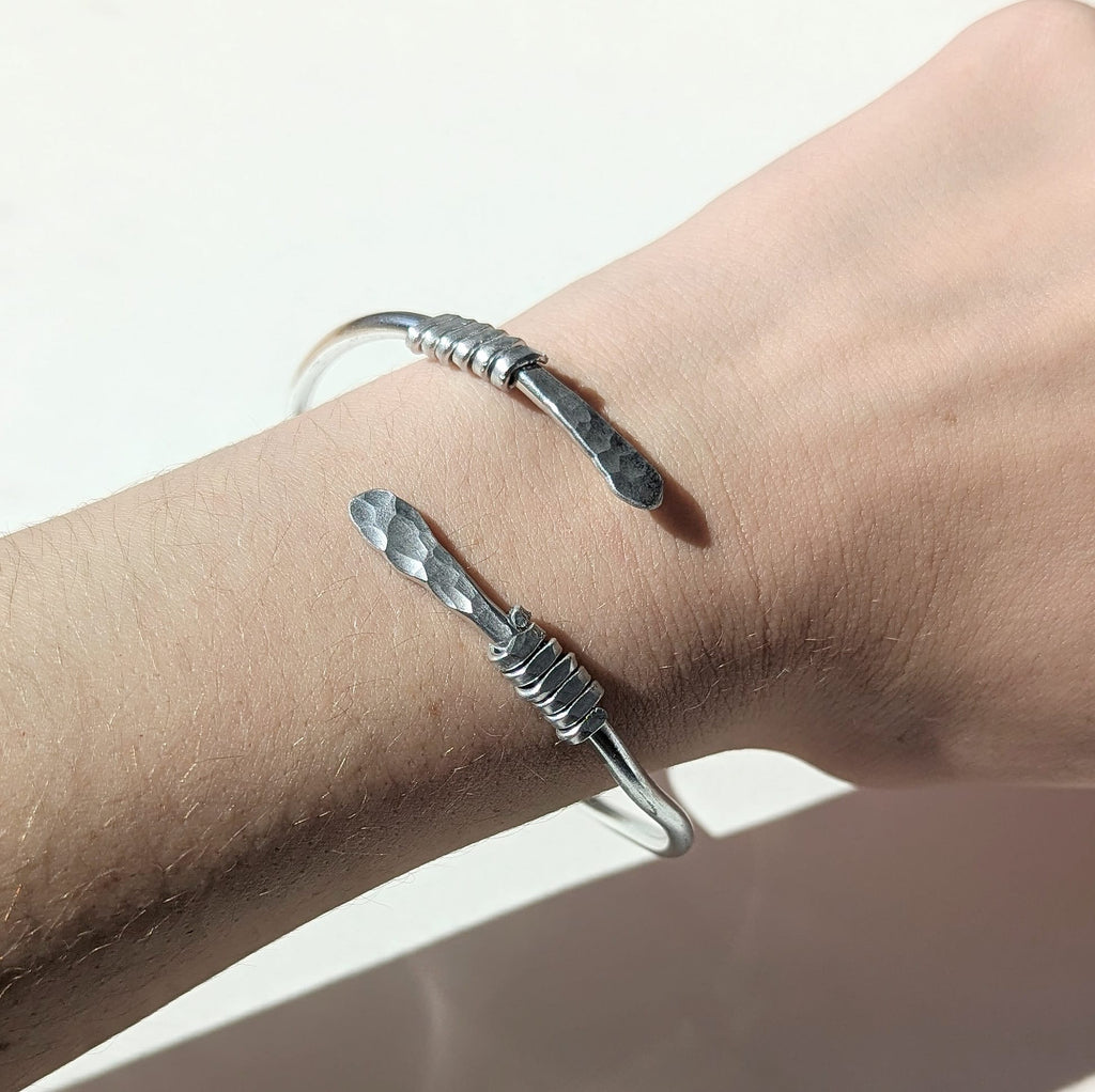 Silver bracelet on a wrist with a plain background