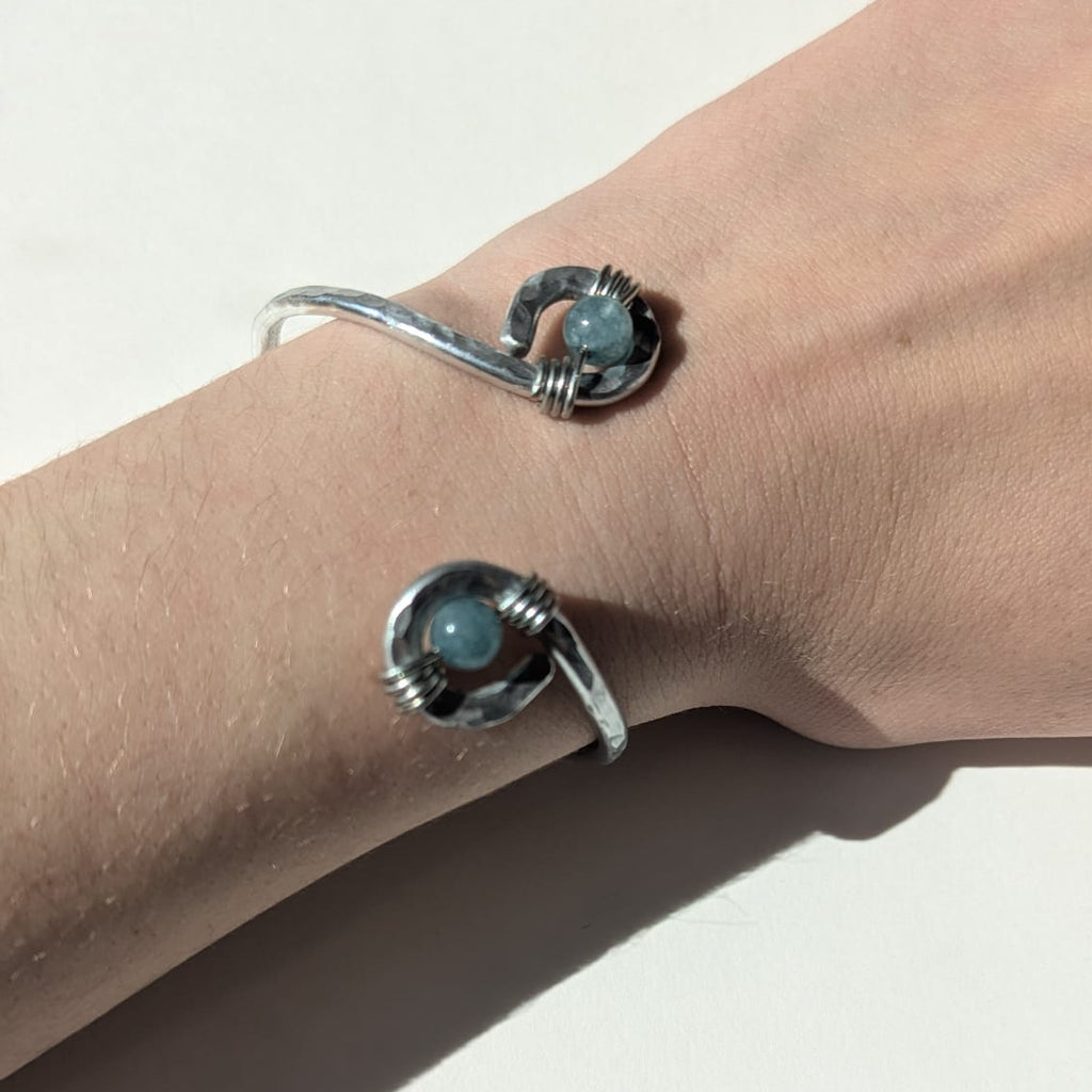 Silver bracelet with turquoise stones on a wrist against a white background
