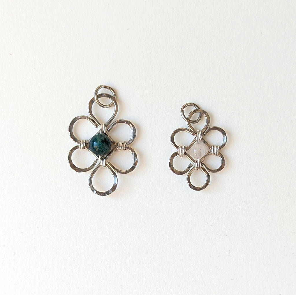 Pair of silver floral earrings with a central gemstone on a white background