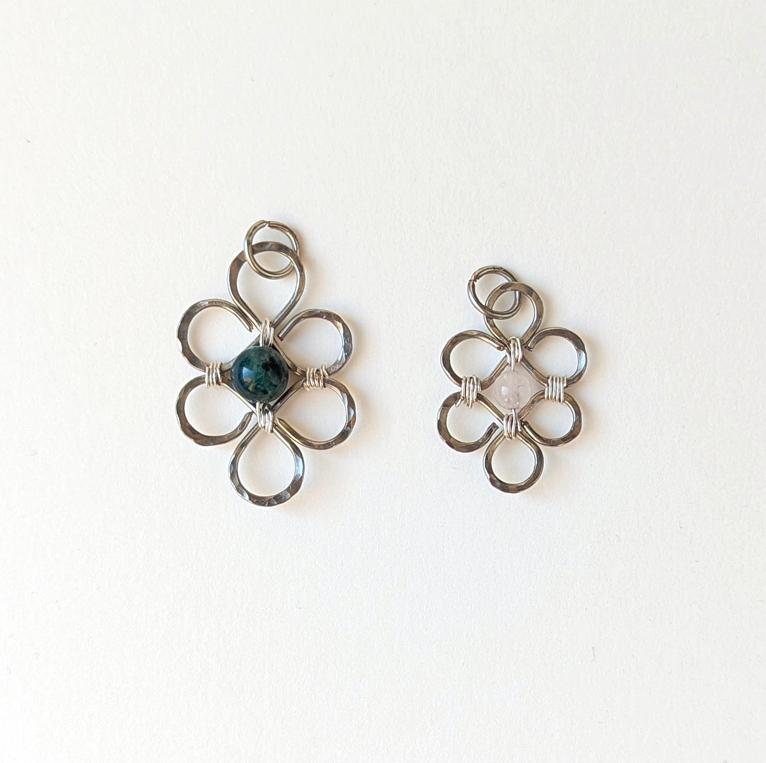 Pair of silver floral earrings with a central gemstone on a white background